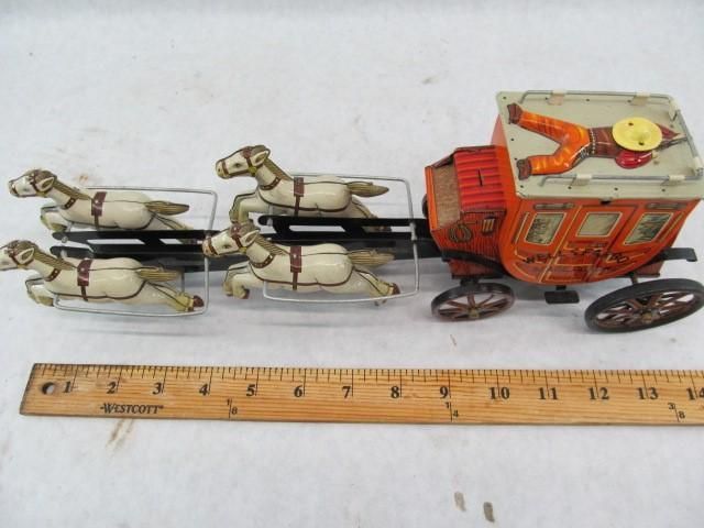 Vintage toy stagecoach with four horses, orange and brown carriage.