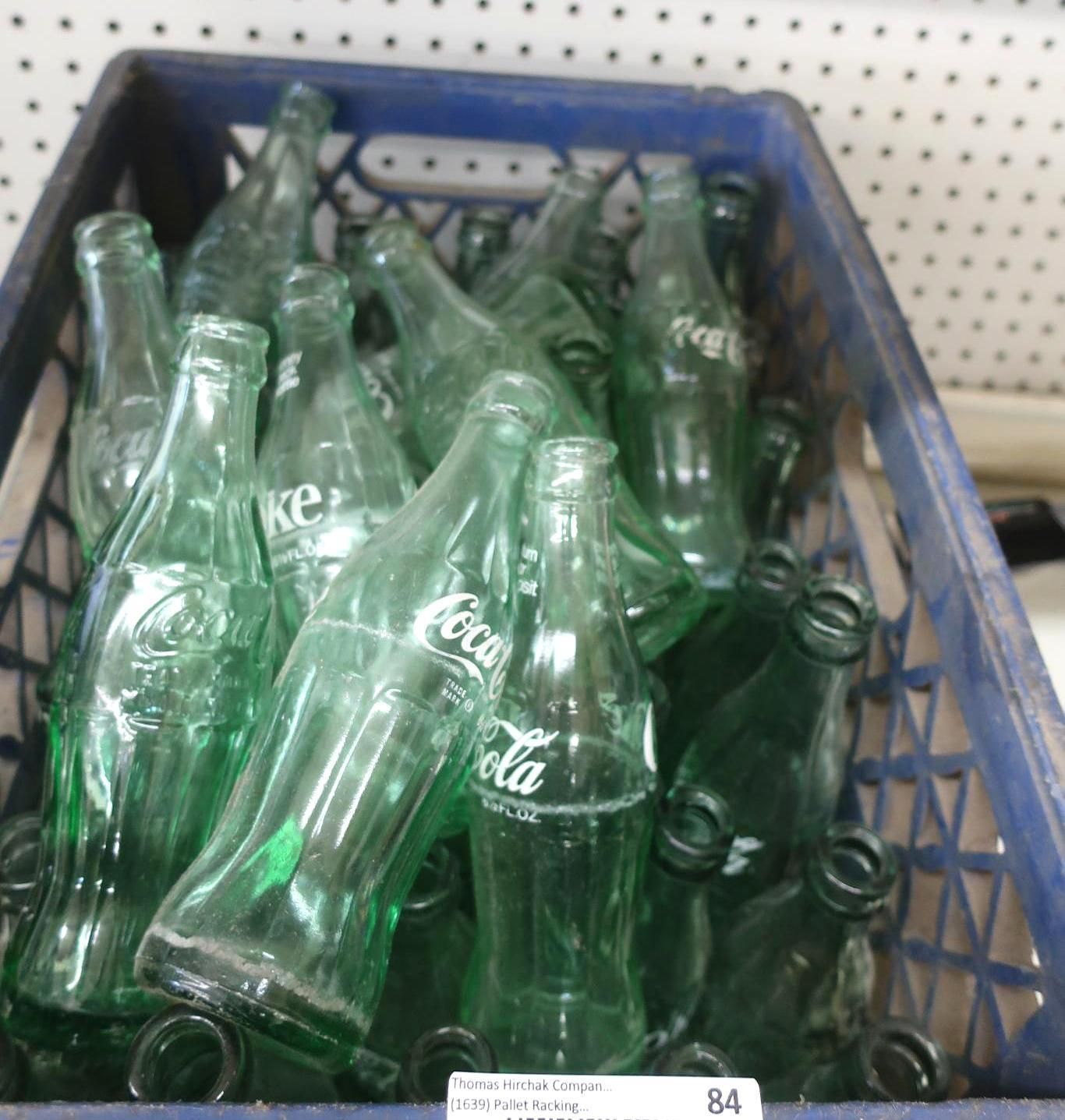 Blue crate filled with empty green Coca-Cola bottles.