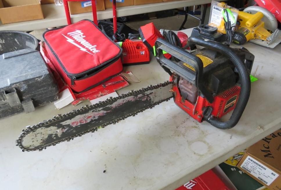 Chainsaw and Milwaukee tool bag on a table with other tools.