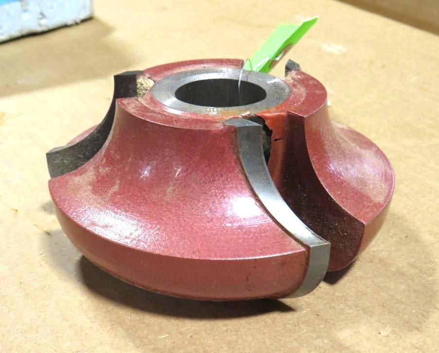 Red router bit with curved blades, for woodworking.