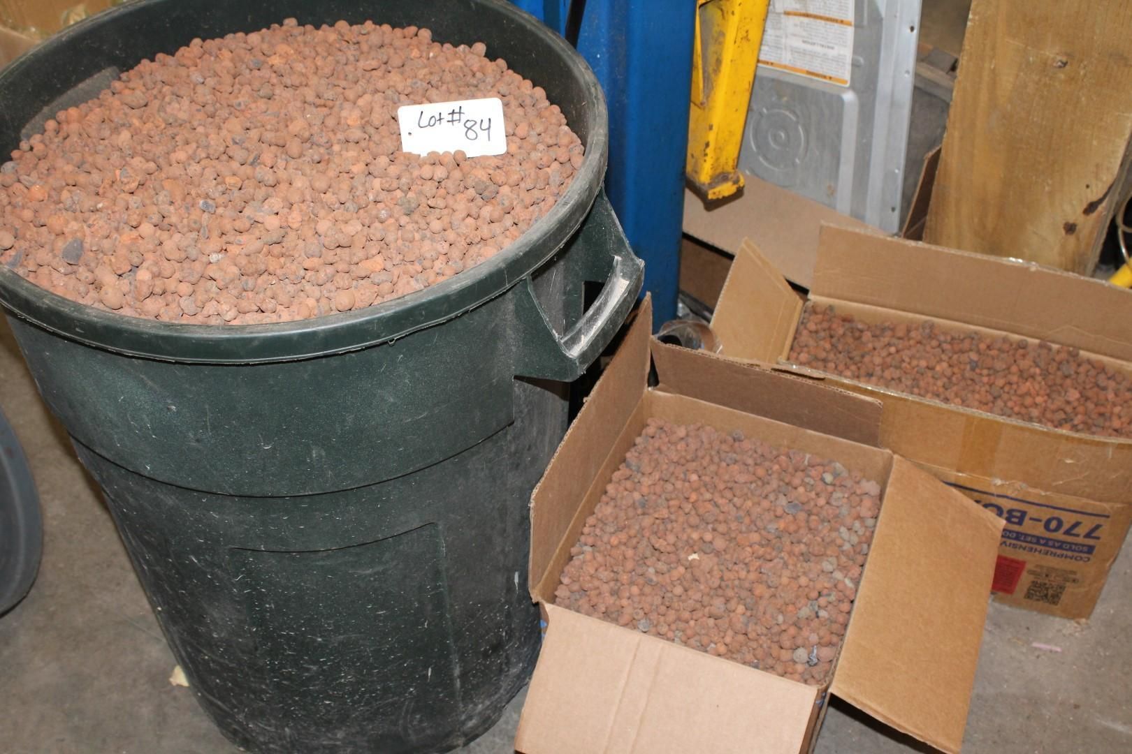 Large black bin and cardboard boxes filled with reddish-brown lava rocks.