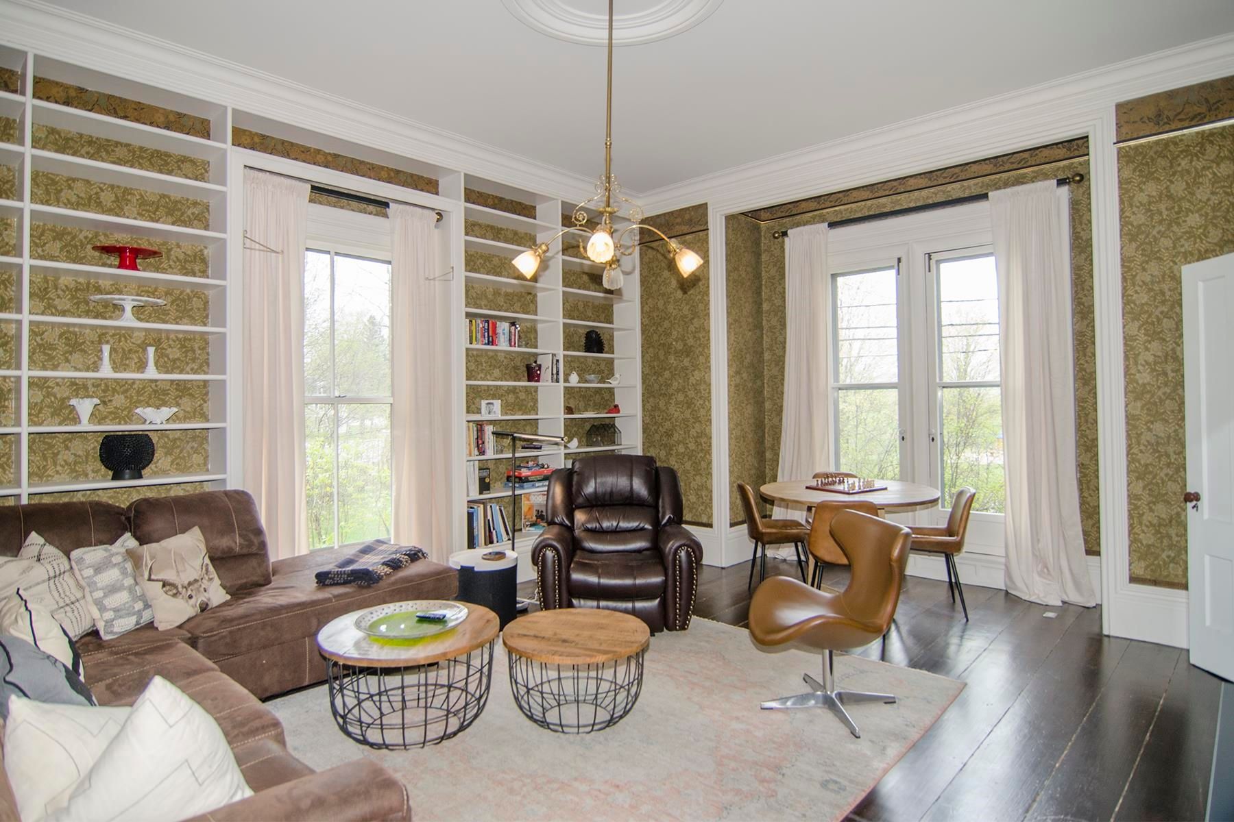 Living room with built-in bookshelves, brown sectional, armchairs, and round table.