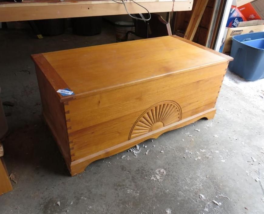 Wooden storage chest with fan carving, light brown, on concrete floor.