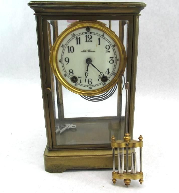 Brass cased clock with a white clock face and detached pendulum.