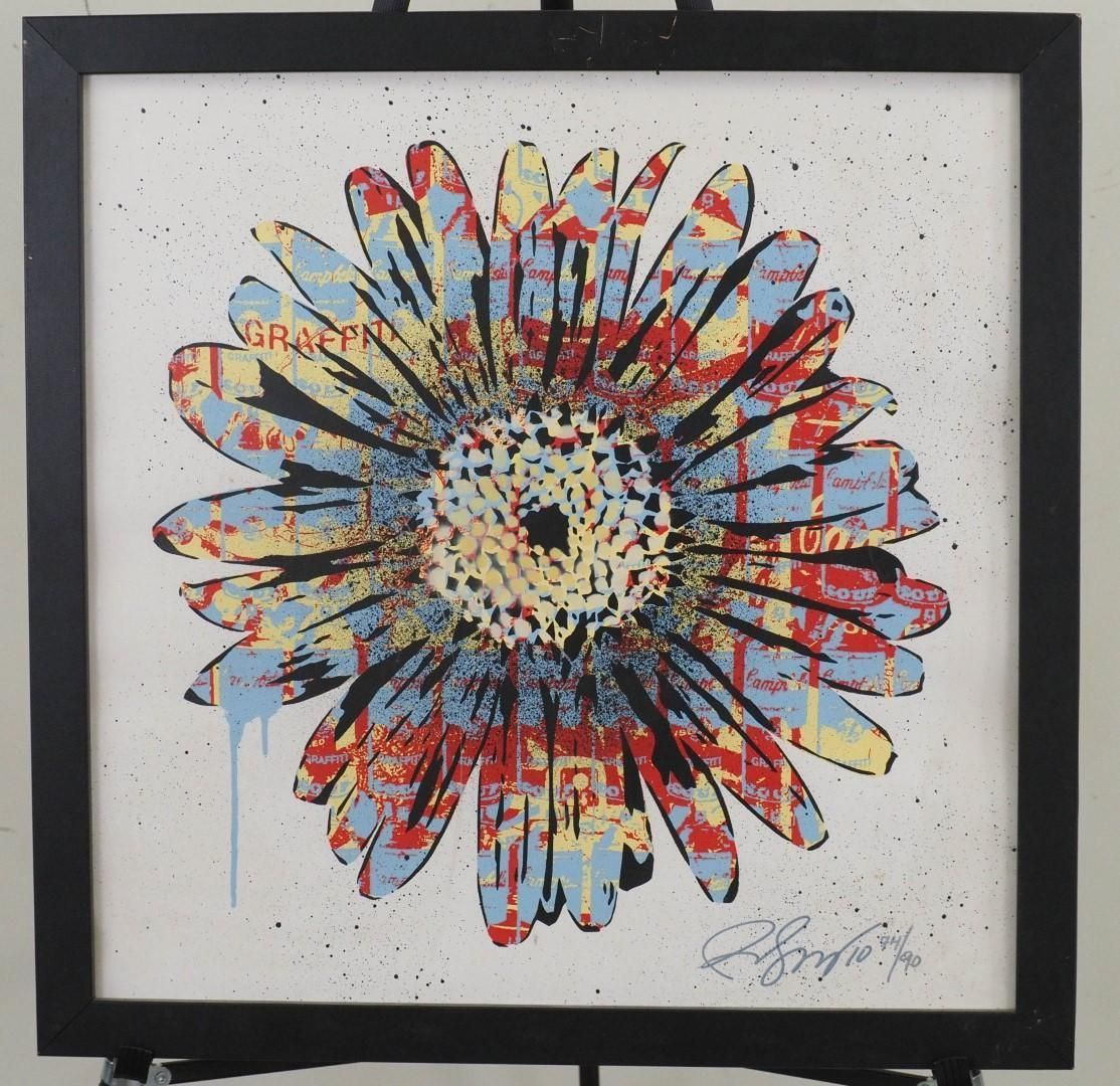 Colorful, layered painting of a daisy against a white background; framed in black, on a black easel.