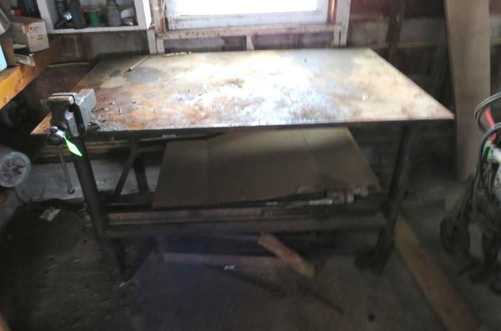 Metal workbench with a vise, inside a workshop.