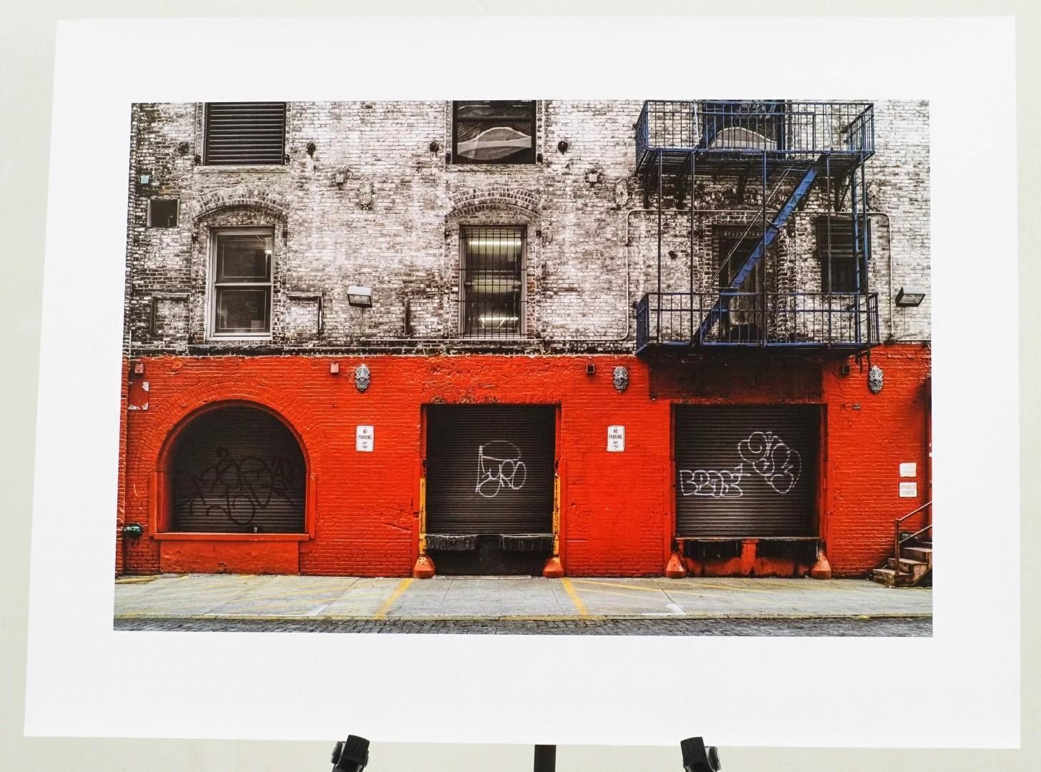 Red-bottomed brick building with black garage doors and a blue fire escape.