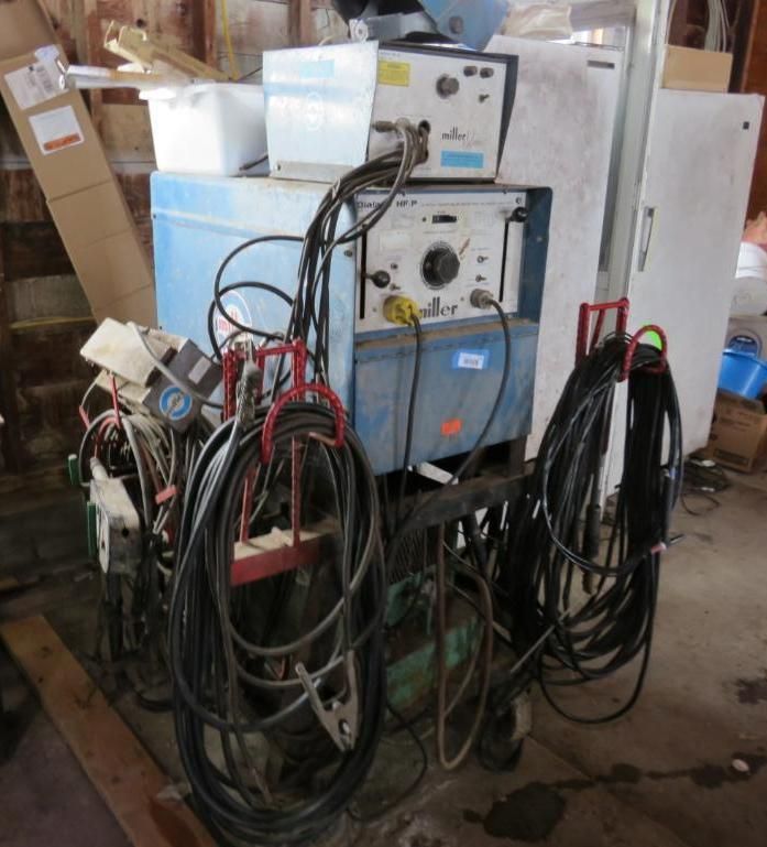 Blue welding machine with coiled cables, cart, and other equipment.