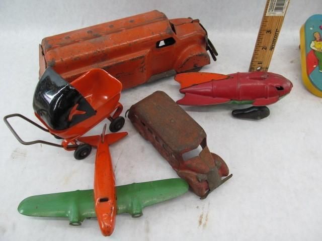 Collection of colorful vintage tin toys, including trucks, planes, and a rocket.