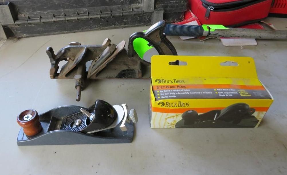 Three woodworking hand planes with one in a box on a concrete surface.