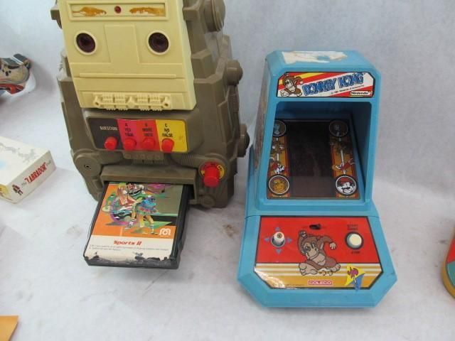 Two vintage toy arcade games: a large beige machine with cartridge slot and a blue Donkey Kong tabletop game.