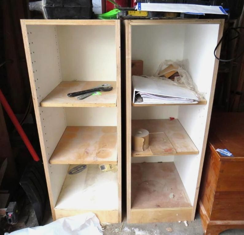 Two unfinished wooden shelves with white interiors. Tools and papers are inside.