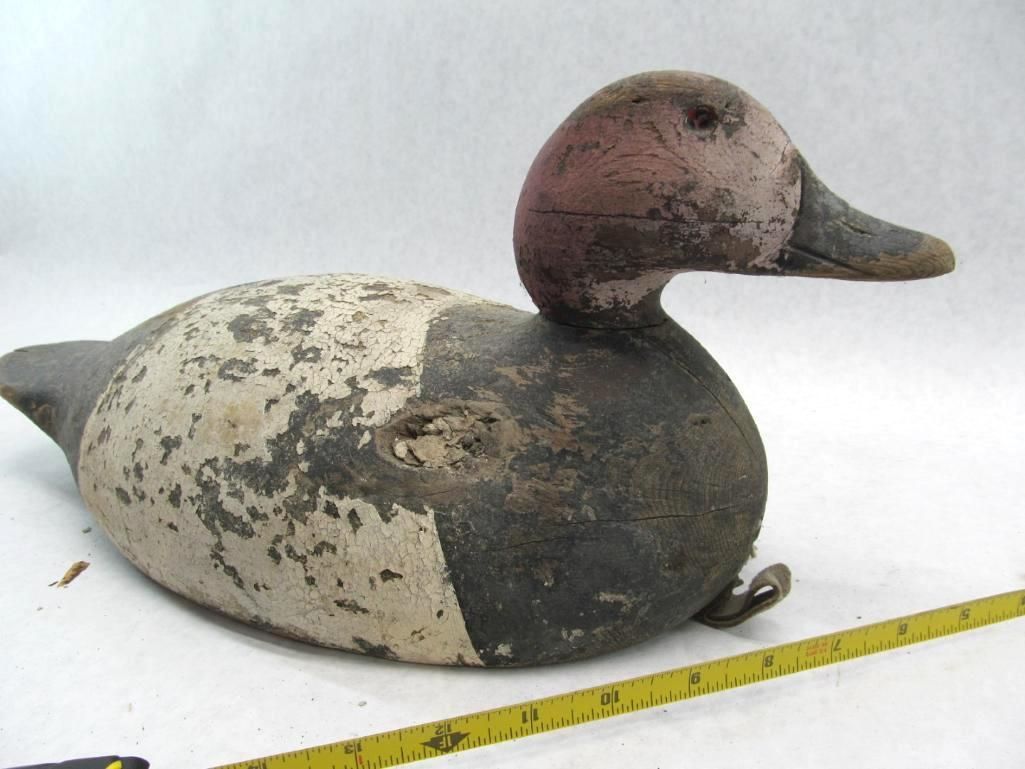 Weathered canvasback duck decoy, white body with dark grey back and head, pink head, lying down.