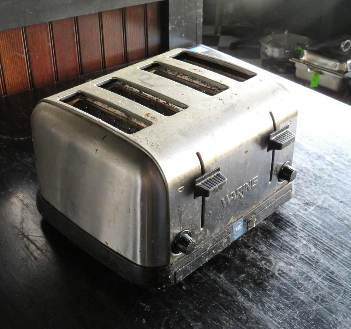 Silver and black four-slice toaster on a dark countertop.