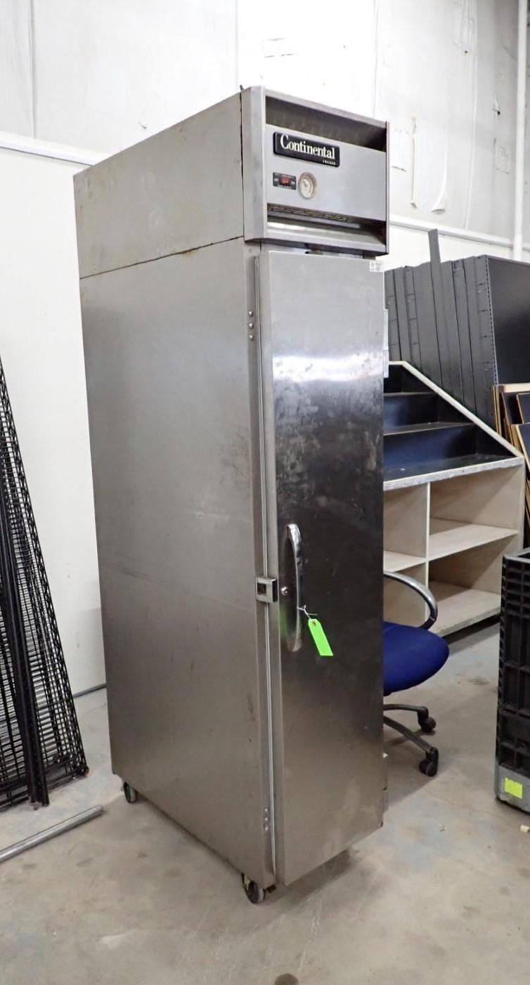 Stainless steel commercial refrigerator on wheels in a warehouse.