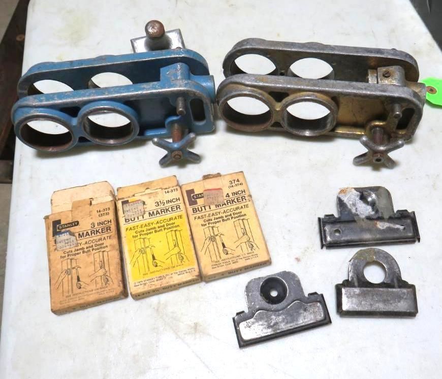 Two metal tools, one blue, one brass, with three holes. Also, three boxes and three metal clips.