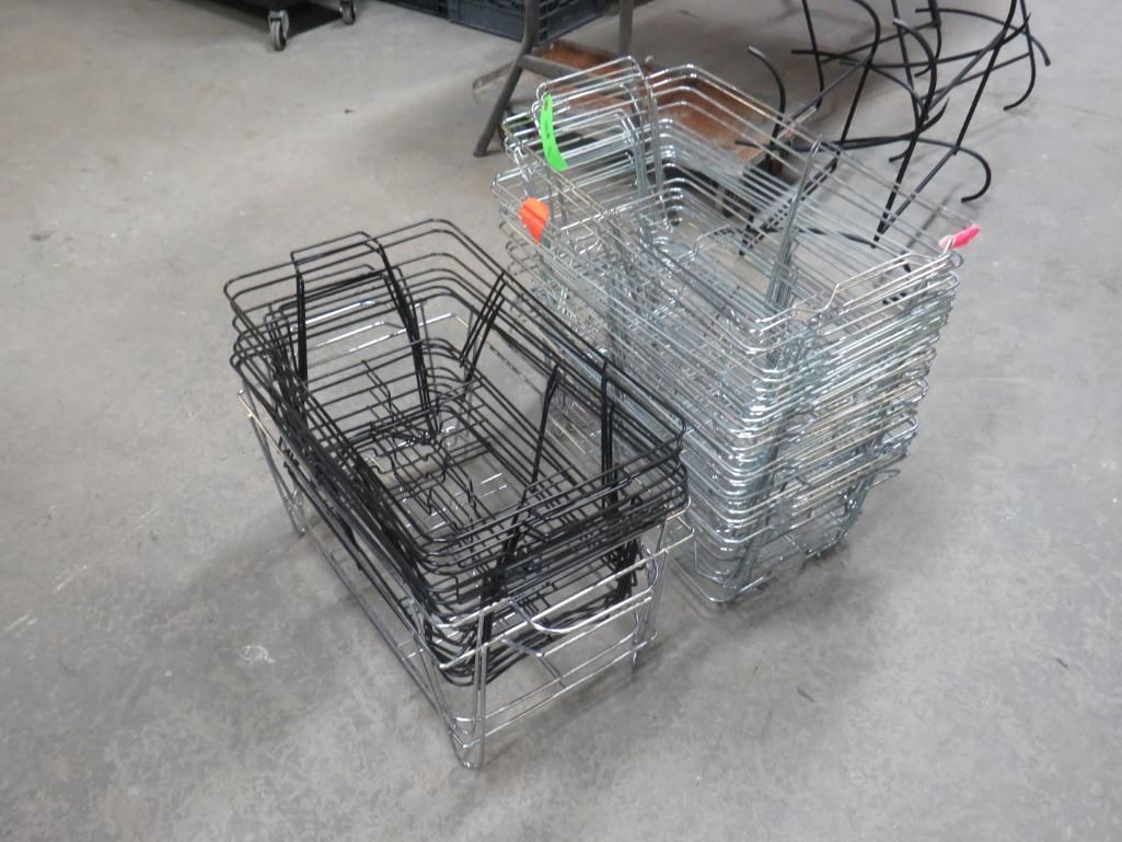 Stacks of wire baskets, some black, some silver, on a concrete floor.