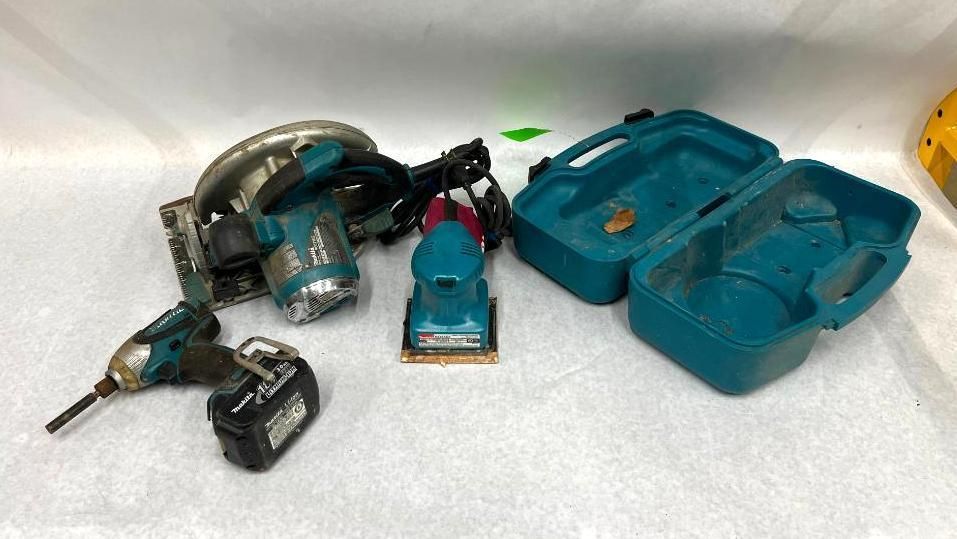 Assorted power tools including a circular saw, sander, drill, and carry case, on a white surface.