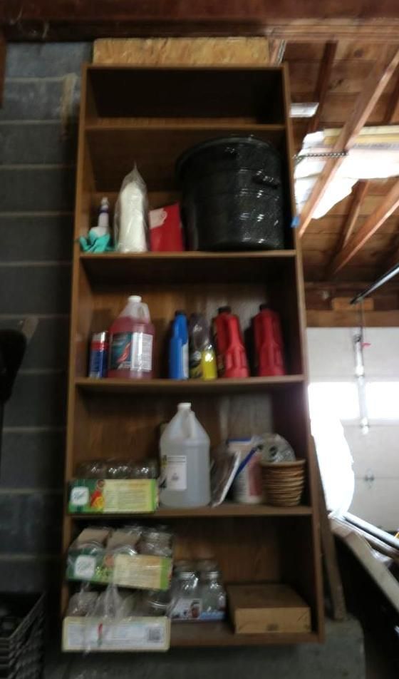 Wooden shelving unit filled with containers and household items in a garage.