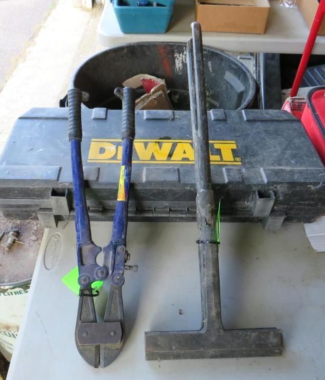 Bolt cutters and a square-shaped metal tool rest on a table.
