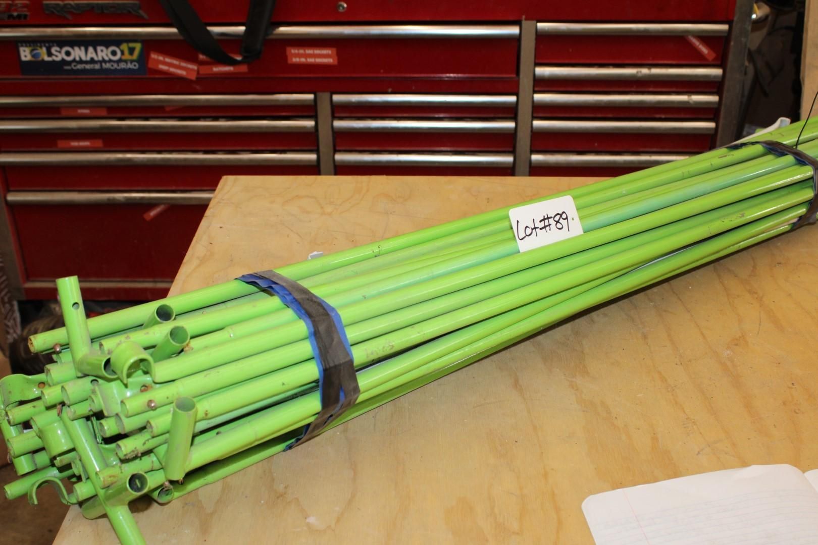 Bundle of neon green metal poles, secured with black straps, on a wooden surface.