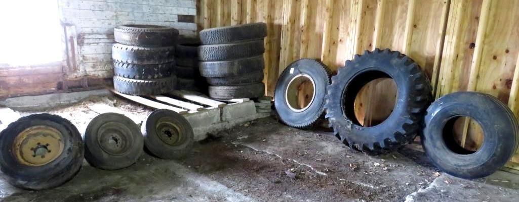 Tires and wheels stacked inside a wooden building.