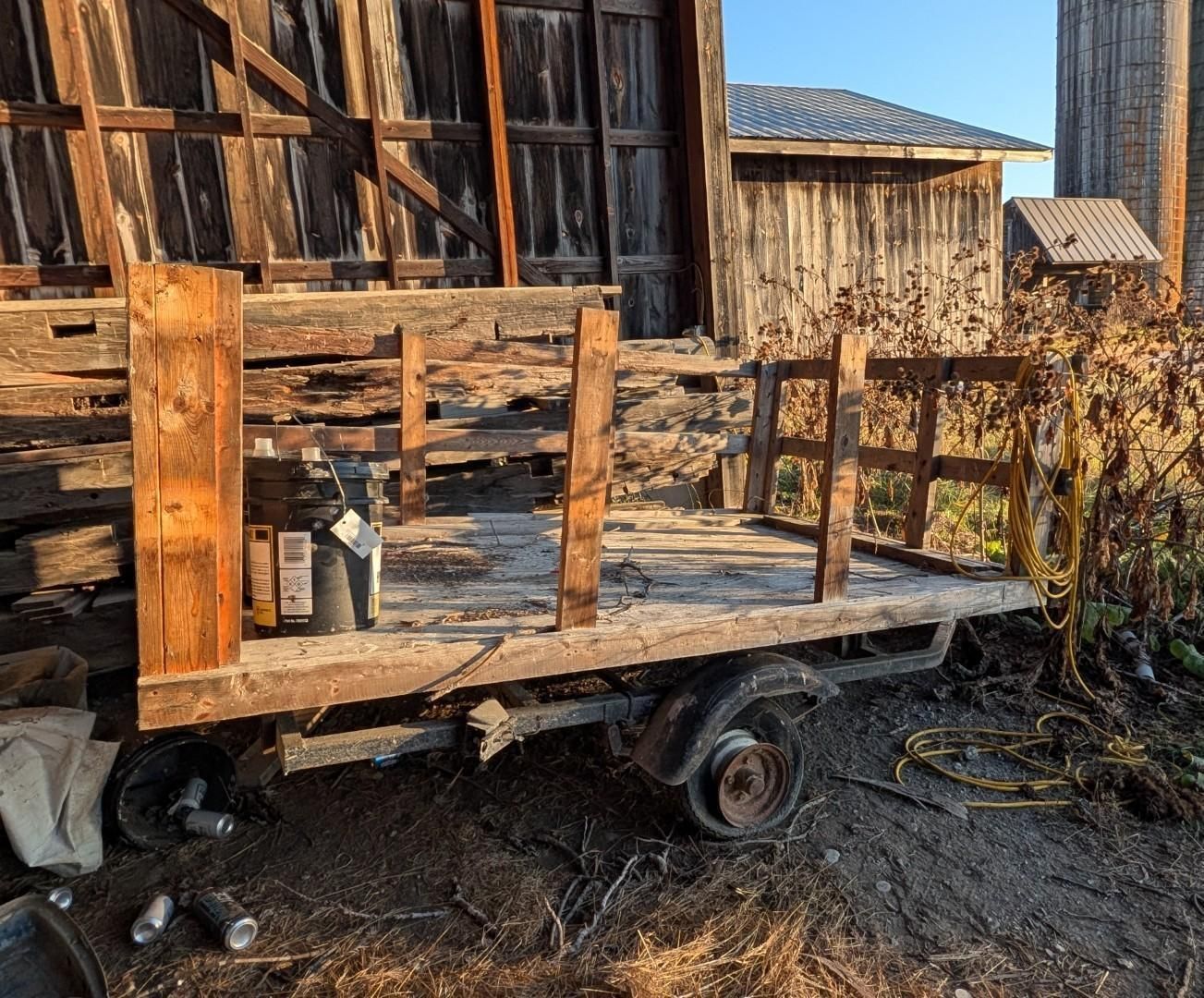 wooden farm porch and barn in a rural setting, with a wheelbarrow and bare vines in winter light