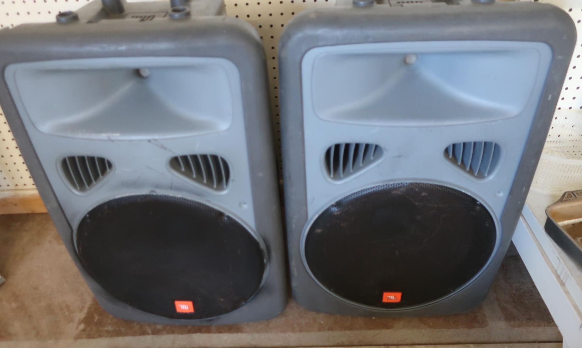 Two gray JBL speakers with black circular fronts, orange logos, and top handles.