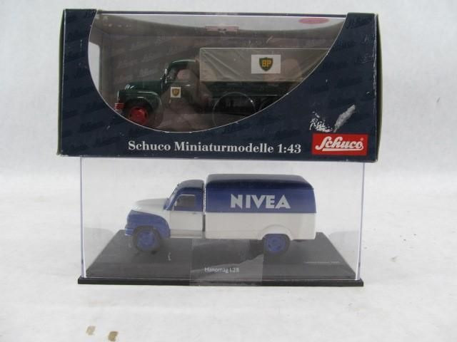 Two Schuco miniature model cars in display cases: a Nivea truck and a green truck.