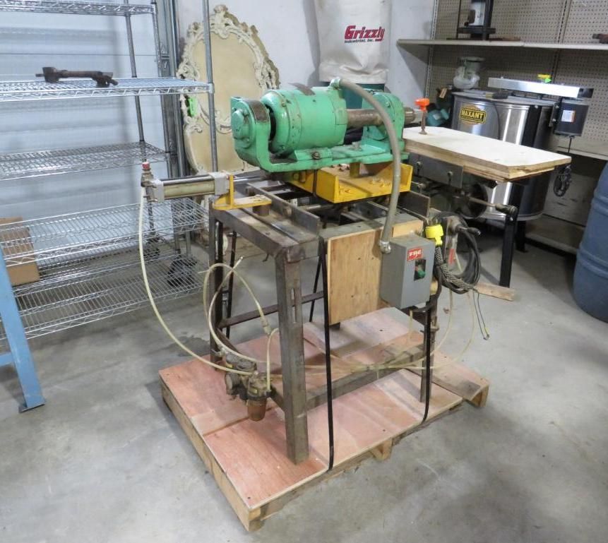 Green industrial machine on a wood platform in a workshop setting.