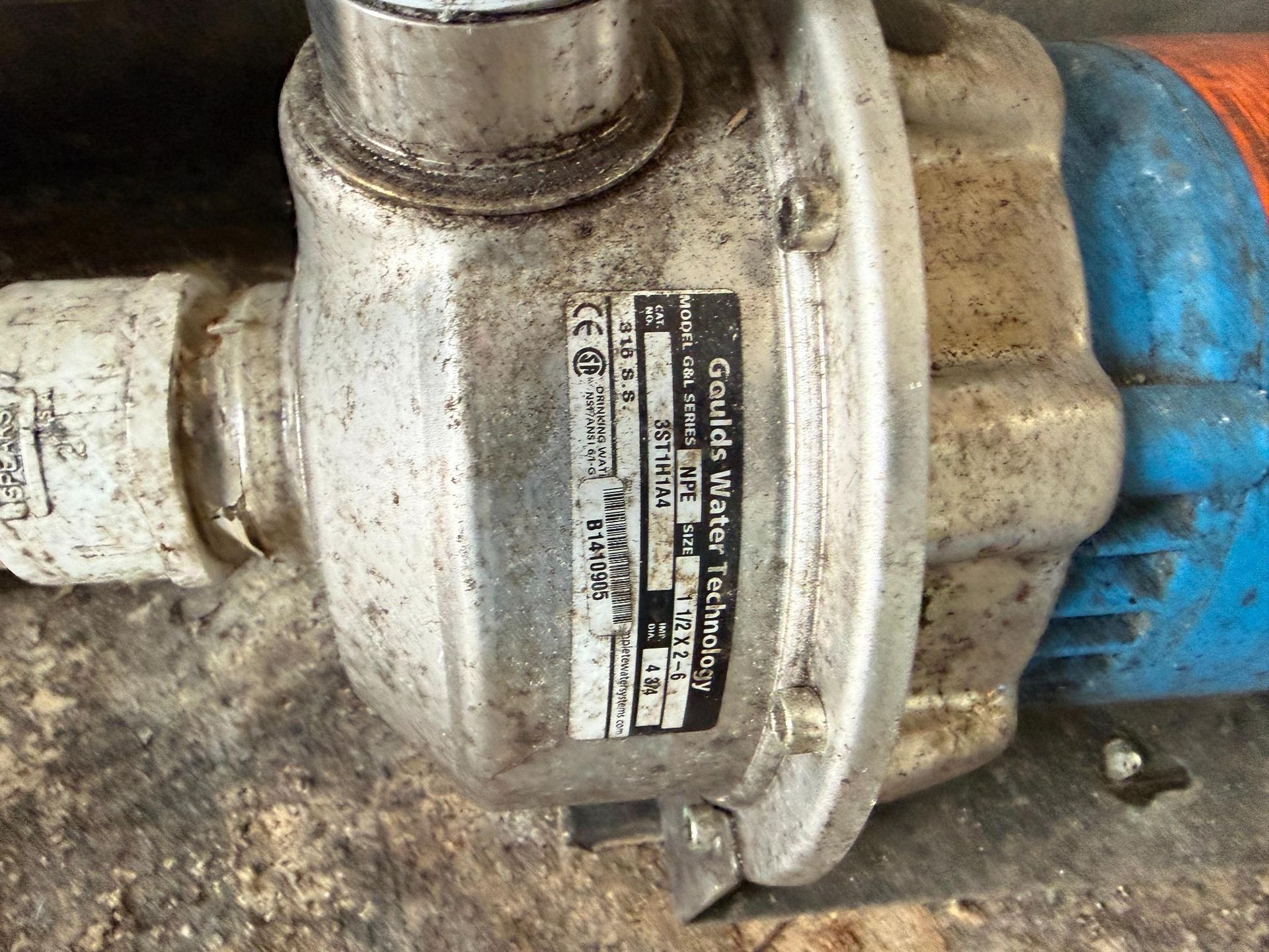 Close-up of a Goulds Water Technology pump with a label. The pump is silver, blue, and orange.