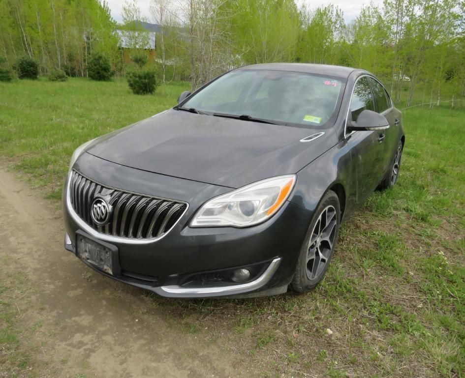 Dark gray Buick Regal sedan parked on grass.
