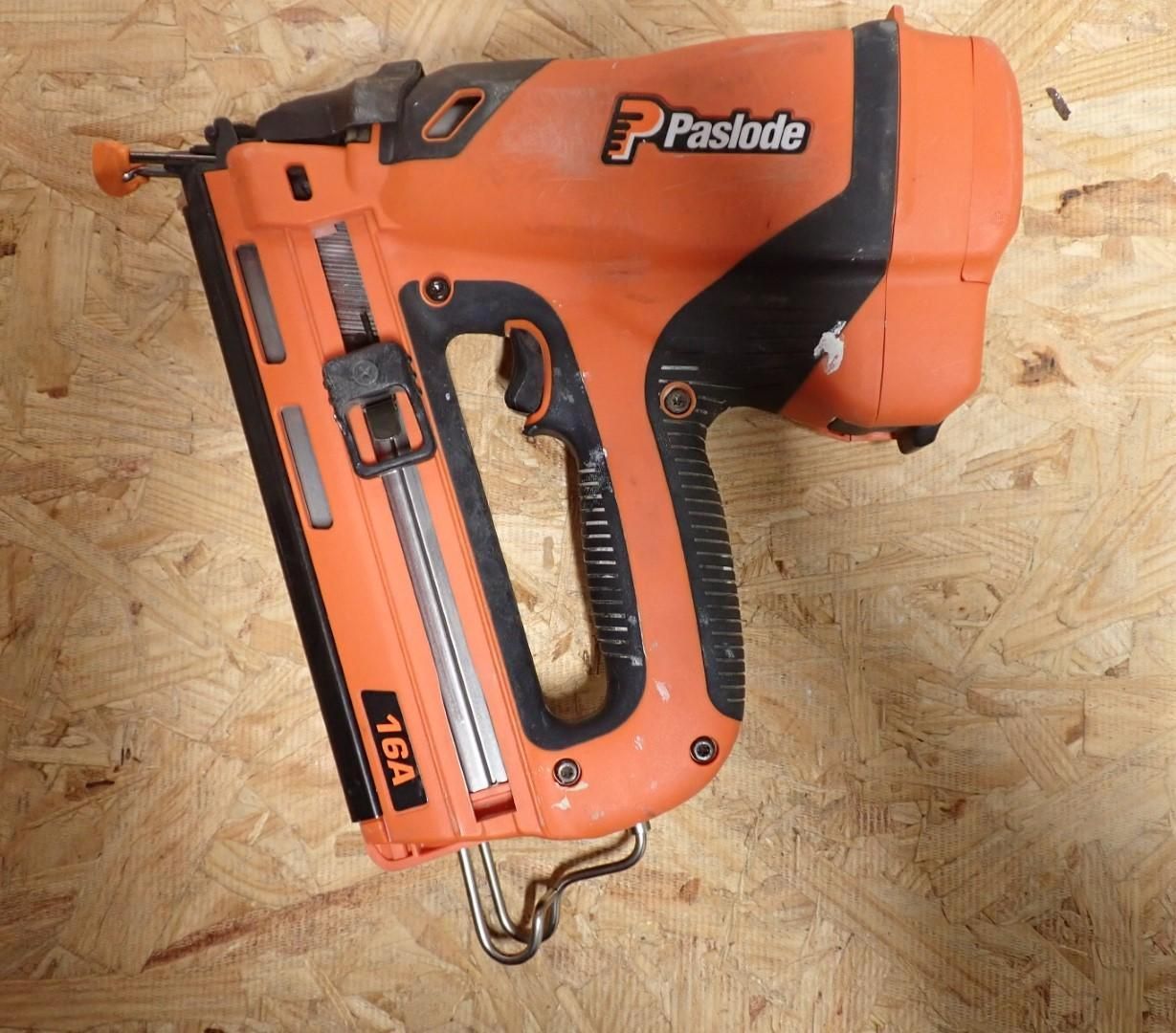 Orange and black Paslode 16GA nail gun on a wood surface.