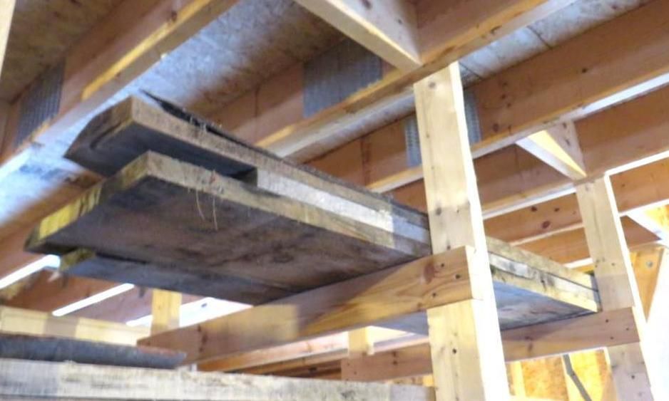 Wooden planks stacked on shelves built into a wooden structure.