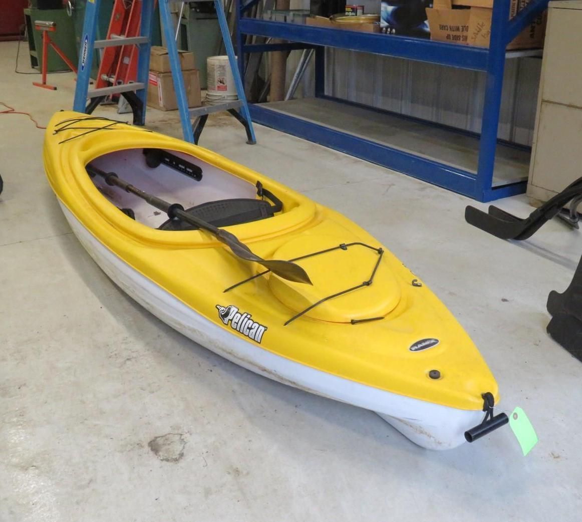 Yellow and white Pelican kayak on a concrete floor with a paddle, indoors.