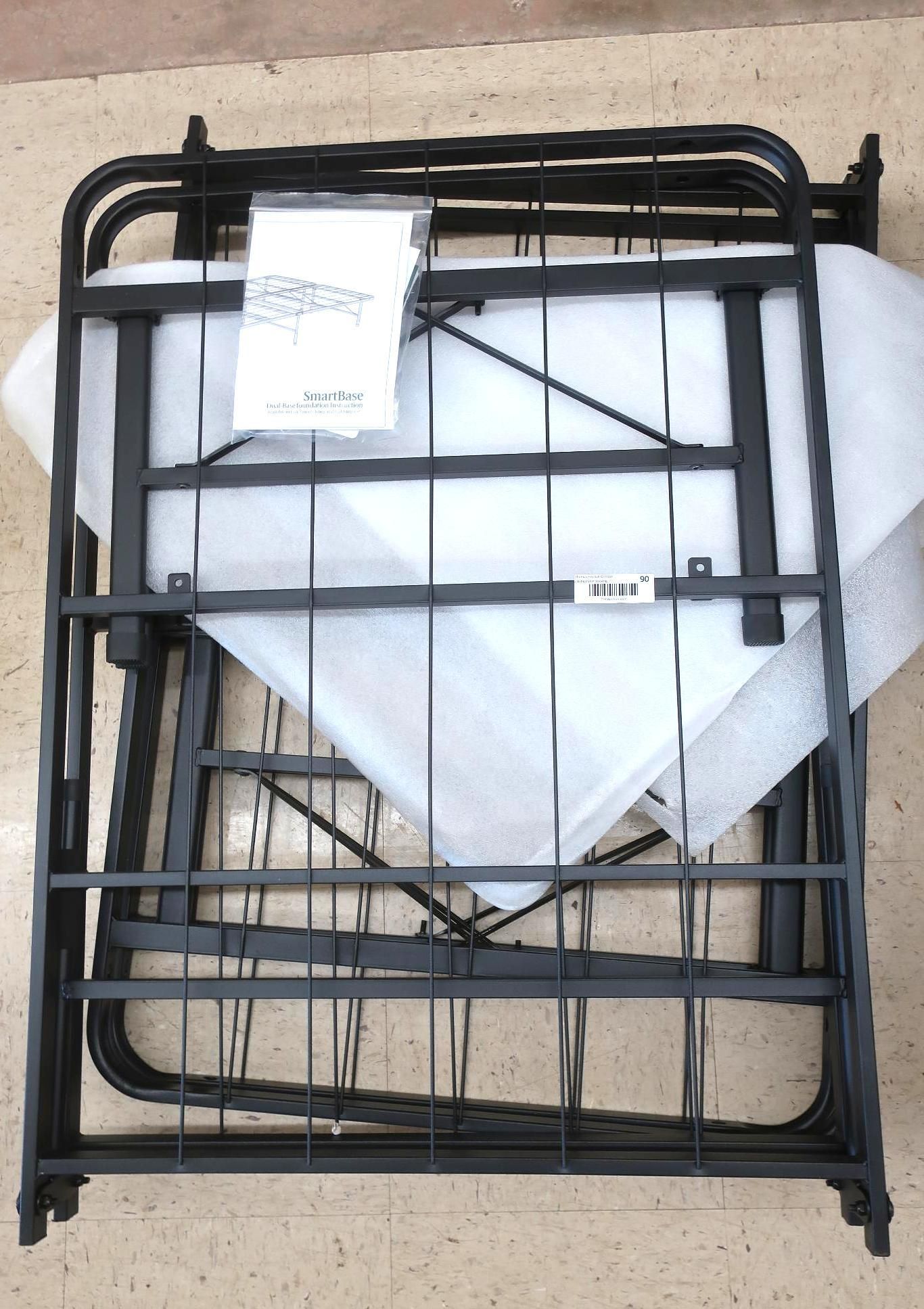 Black metal bed frame, folded, with instructions and white packing.