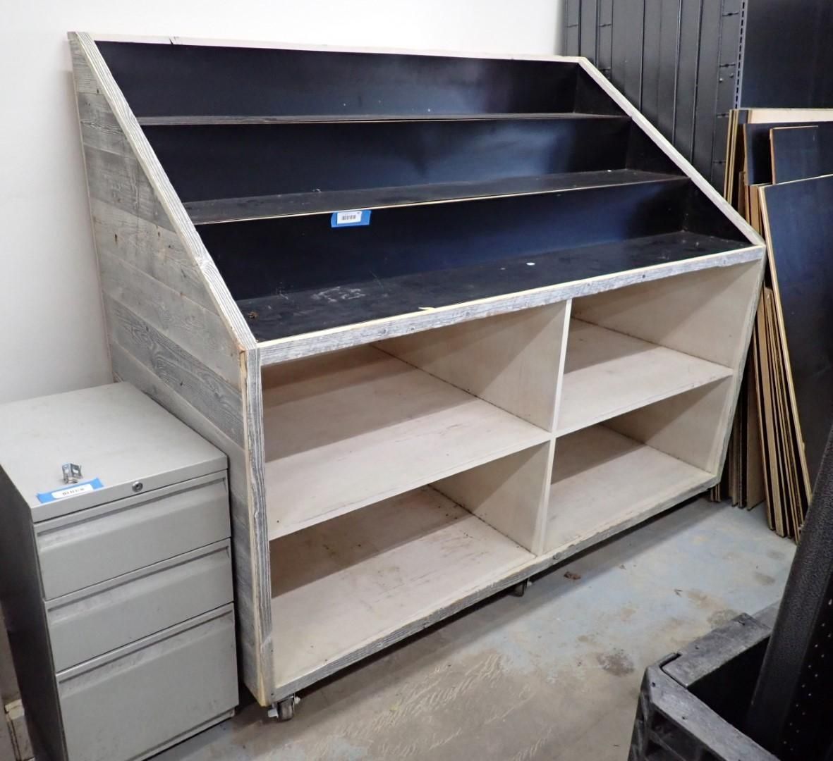 Wooden display unit with slanted shelves, four lower compartments, on wheels.