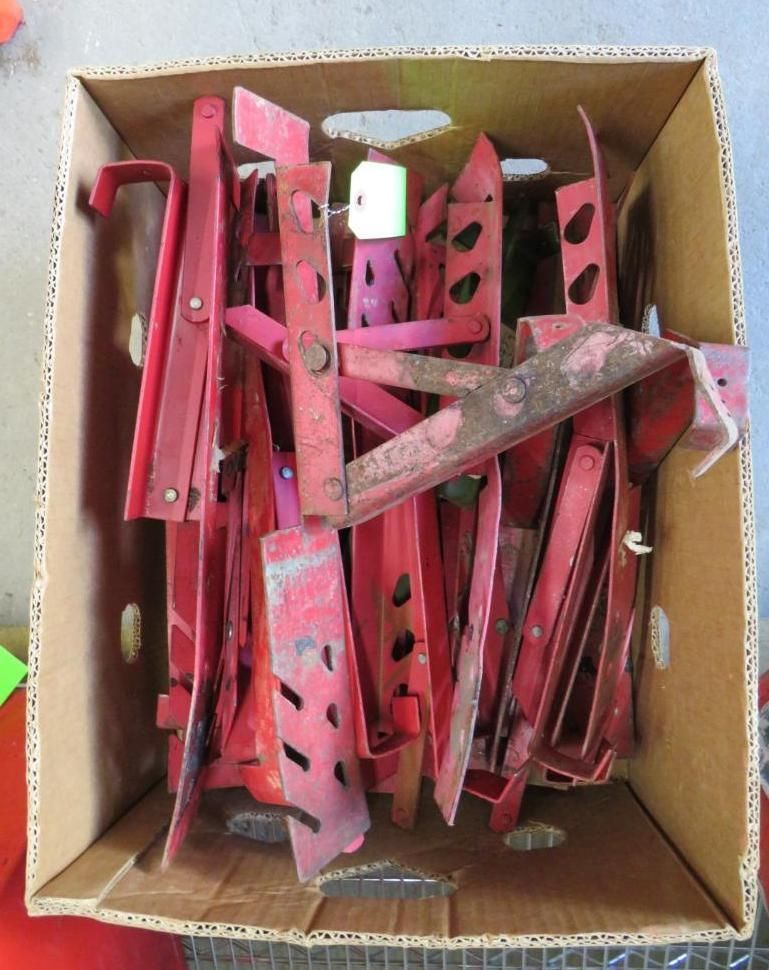 Red metal brackets in a cardboard box.