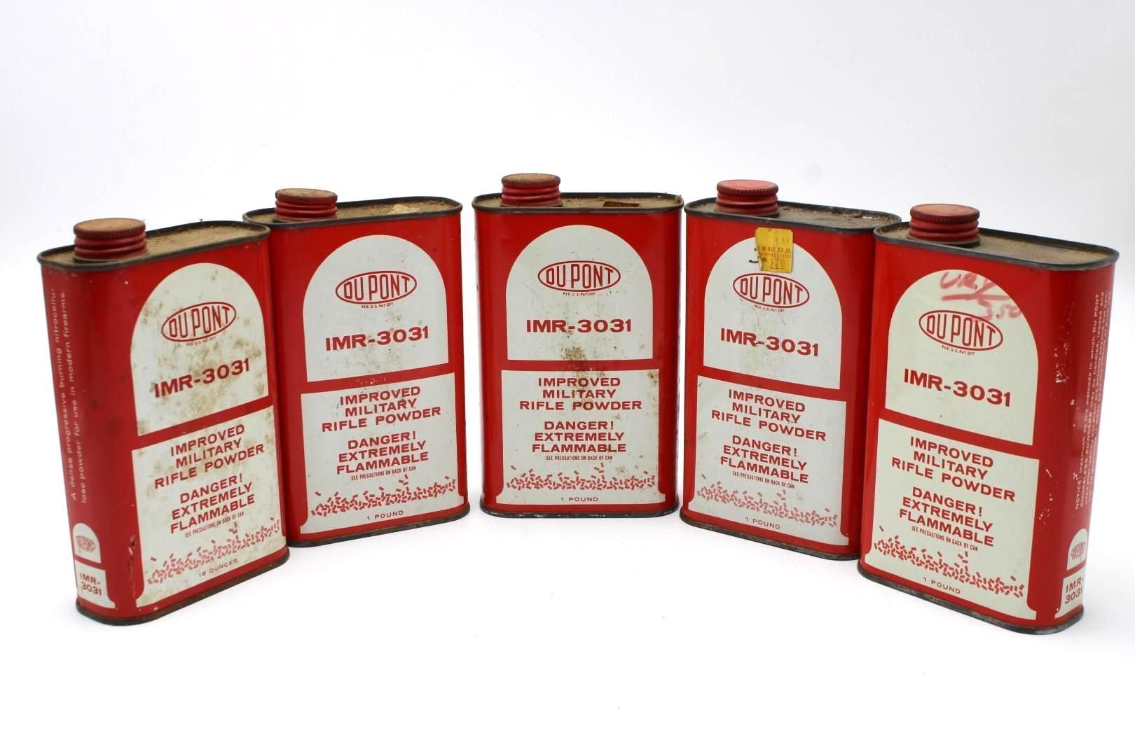 Five red metal oil cans arranged in a row on a white background