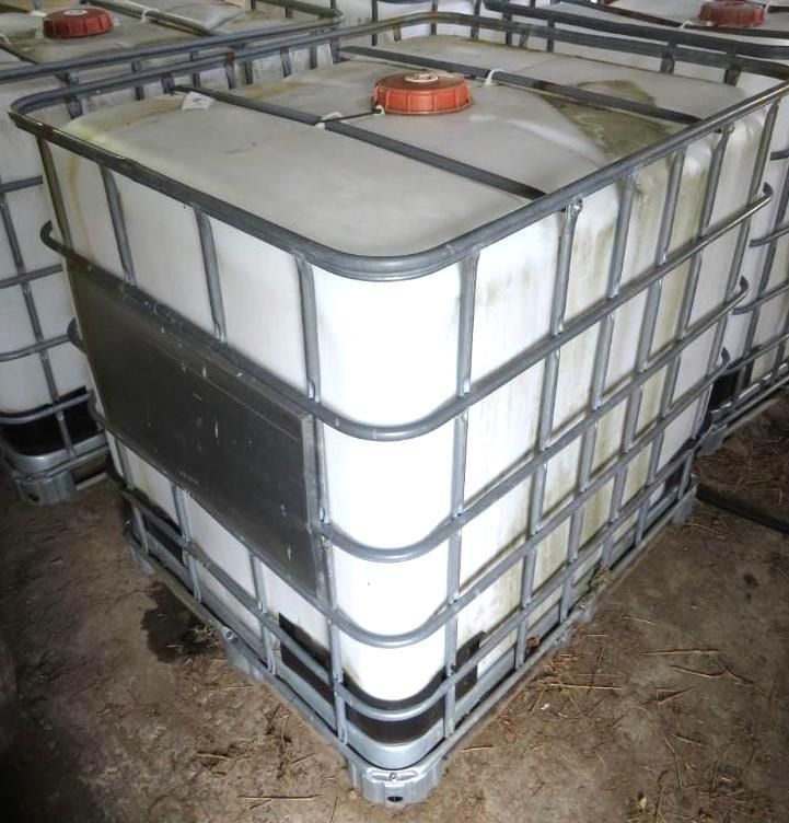 White intermediate bulk container, in a metal cage. Orange cap on top.