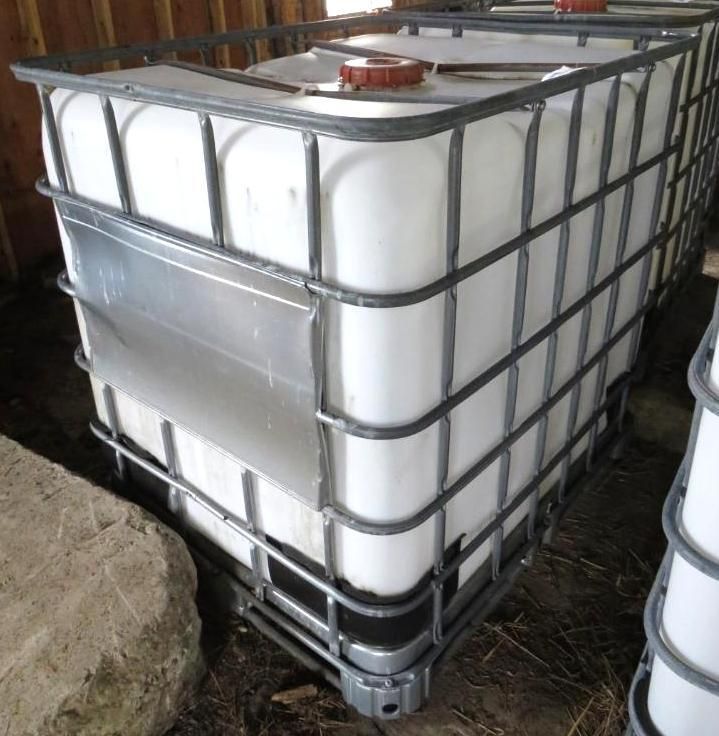 White plastic IBC tote in a metal cage.