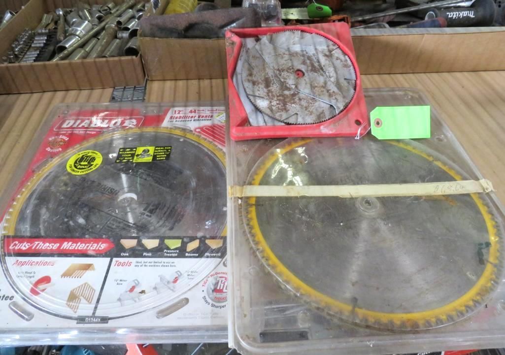 Three circular saw blades, two in packaging, one in a red case, on a wooden surface.