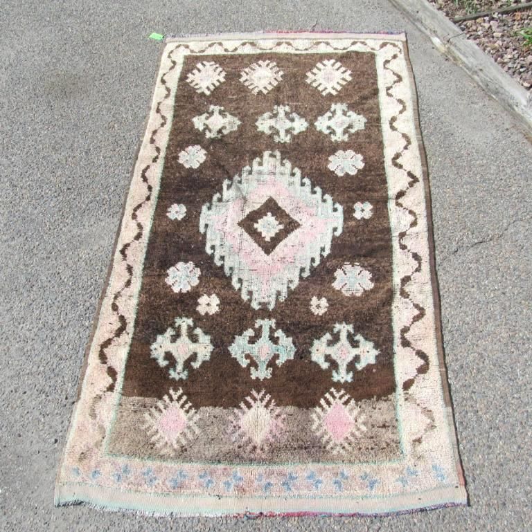 Brown and beige patterned rug on a gray surface, with geometric and floral designs.