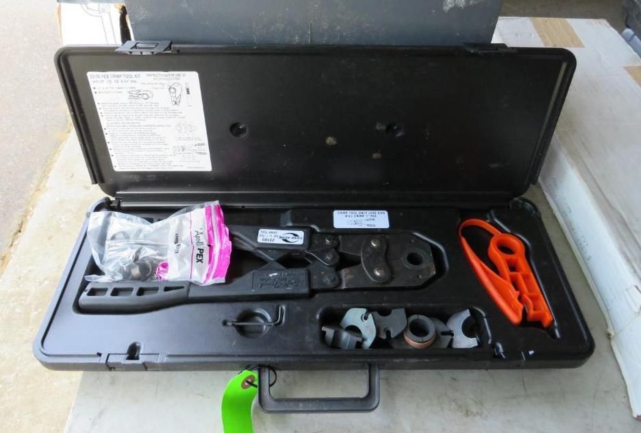 Black case holding crimping tool, fittings, and orange handle tool on a concrete surface.