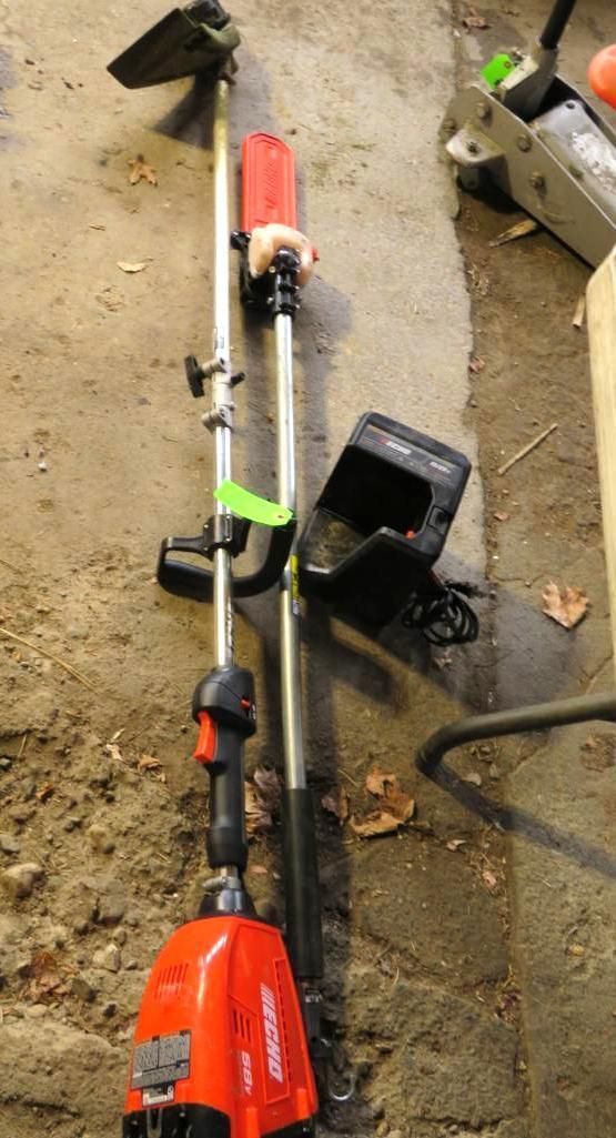 Red and black Echo weed wacker on concrete floor, with battery charger.