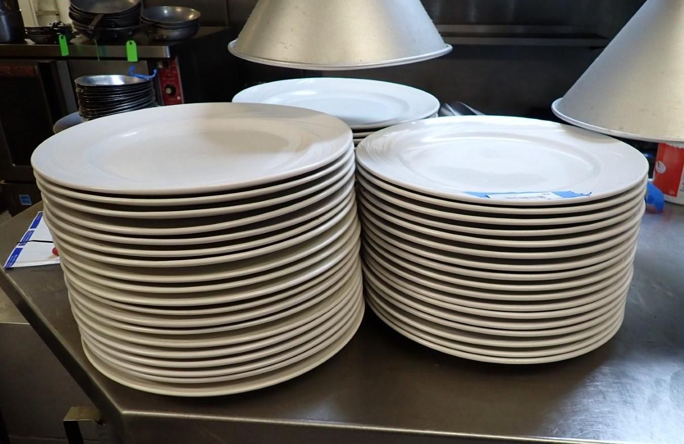 Stacks of white dinner plates on a stainless steel surface.