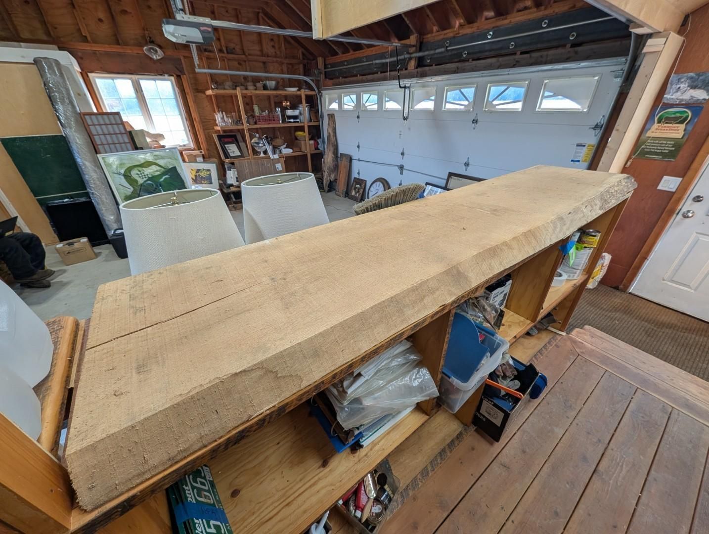Long wooden beam resting across a workshop table inside a garage-like space