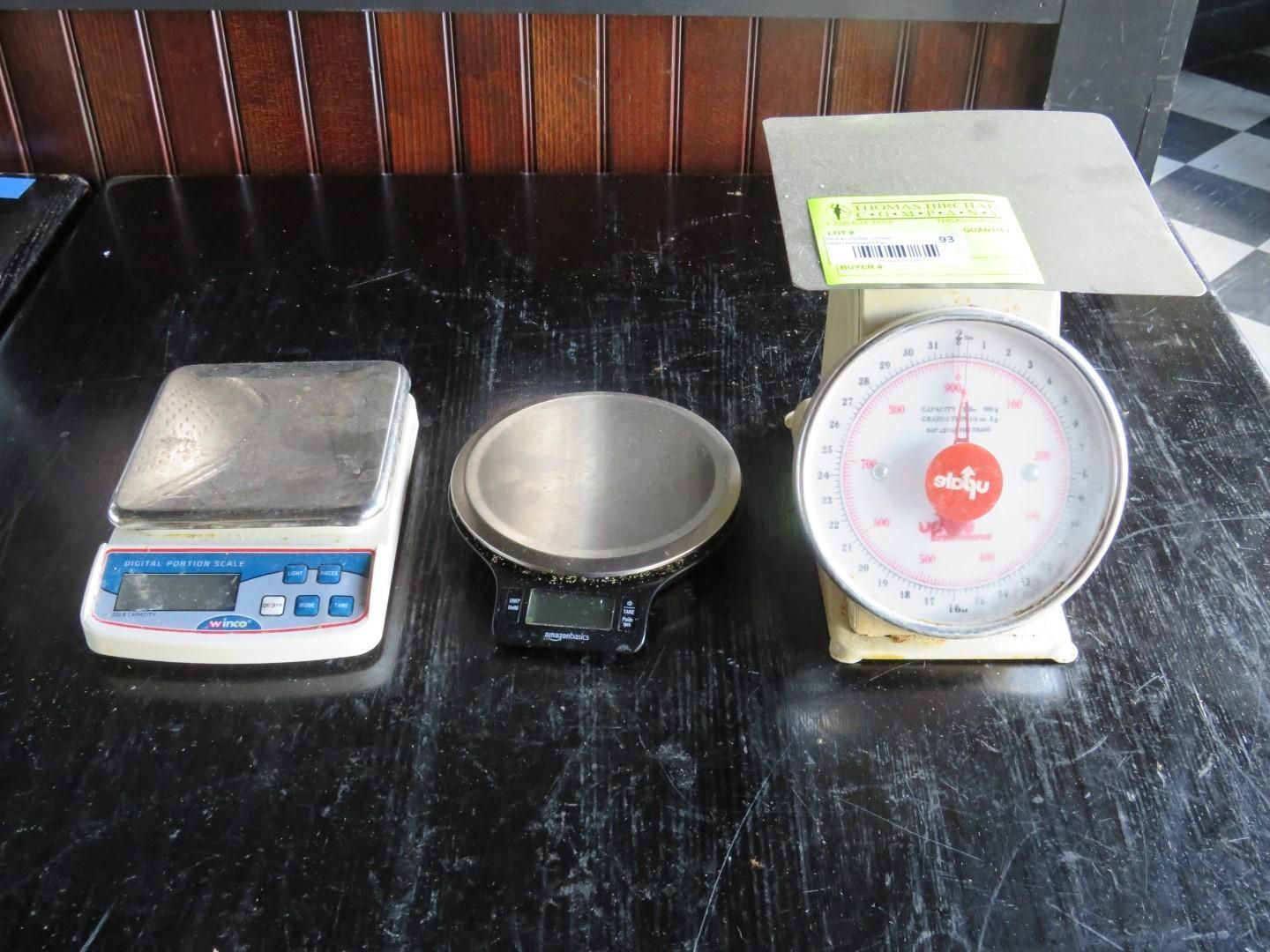Three different scales on a dark surface: a digital scale, a small circular scale, and a vintage circular scale.