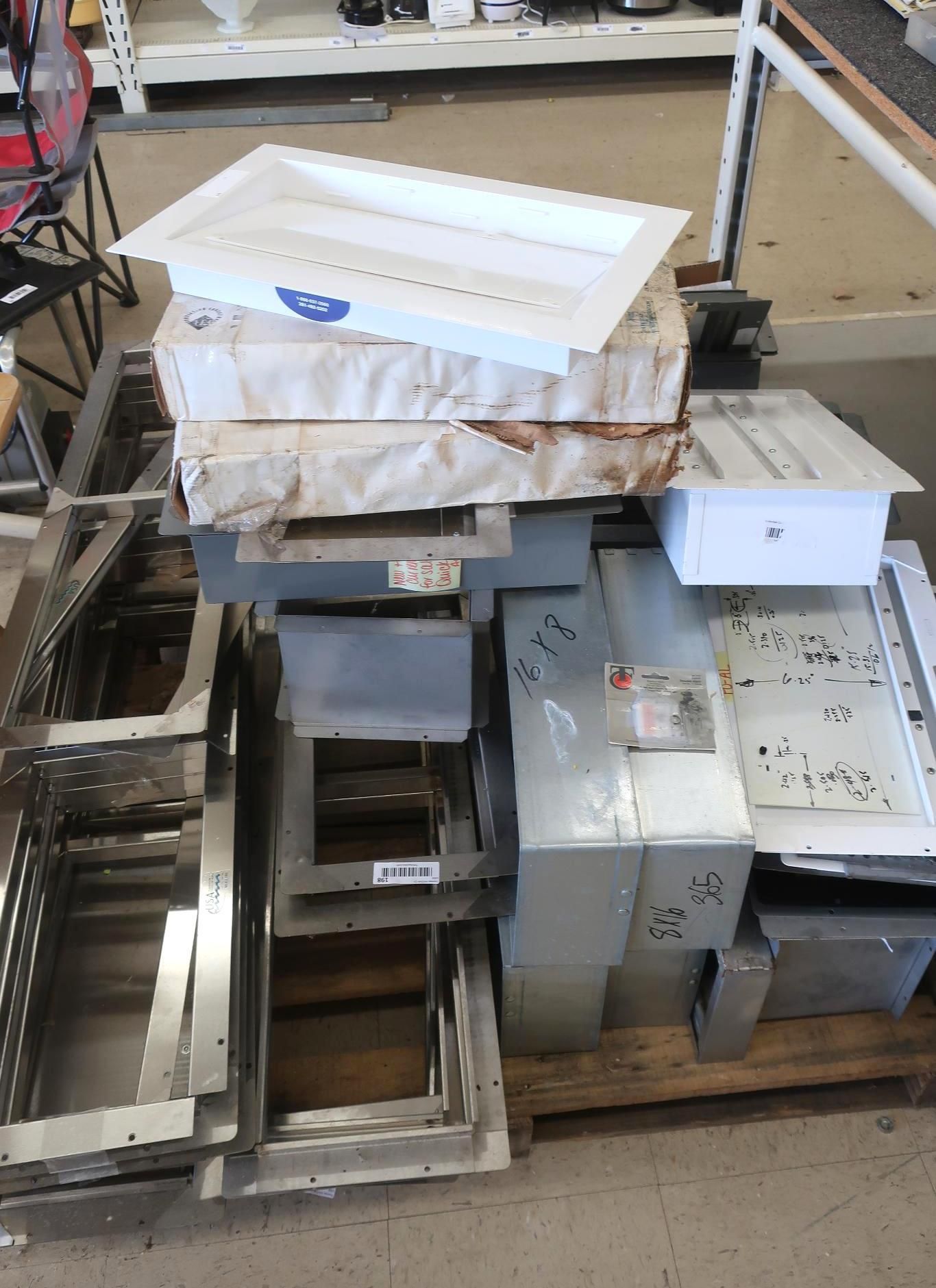 Metal frames and rectangular boxes on a wooden pallet in an industrial setting.