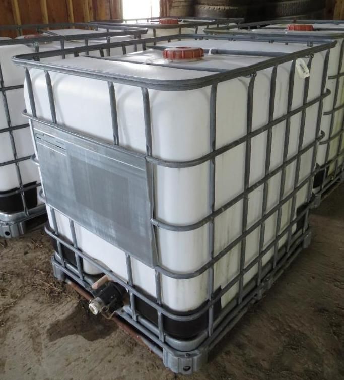 White IBC tote tank in a metal cage, with a valve, and a red cap.